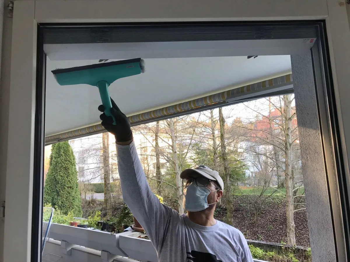 Ostad Mitarbeiter reinigt ein Fenster bei einer Umzugsreinigung